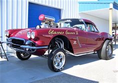 an old fashioned car is parked in front of a building with its hood up and engine on