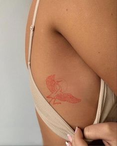 a woman's back with a tattoo on her left shoulder and an orange bird in the middle