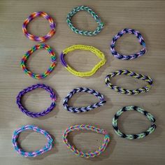 several different colored bracelets laid out on a wooden table with one knot in the middle