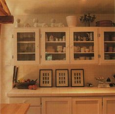 a kitchen with white cabinets and pictures on the wall