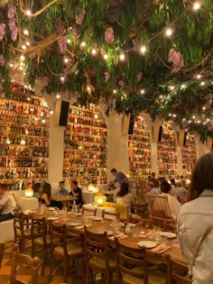 people sitting at tables in a restaurant with lots of books on the walls