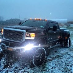 a black truck with lights on driving in the snow