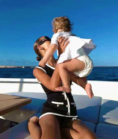 a woman holding a baby while sitting on top of a boat