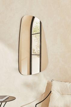 a mirror hanging on the wall next to a table with a chair in front of it