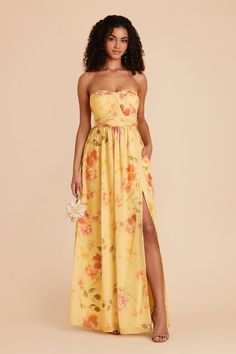 a woman wearing a yellow floral print strapless dress with high slit and side split