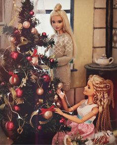 two dolls are decorating a christmas tree