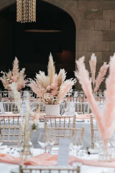 the tables are set with white linens and tall vases filled with pink flowers