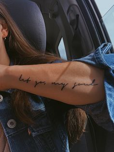 a woman with a tattoo on her arm sitting in a car