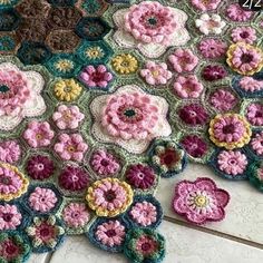 crocheted flowers are arranged on the floor in this photo, and one has been made into a blanket