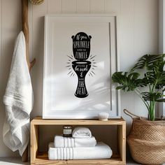 a bathroom with towels and plants on the shelf next to it is a framed poster