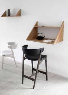 two chairs and a desk in a white room with shelves on the wall behind them