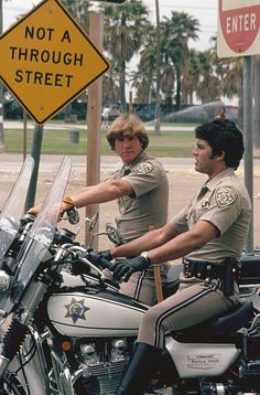 two police officers sitting on their motorcycles in front of a sign that says not a through street