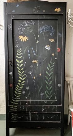 a black cabinet with flowers painted on it