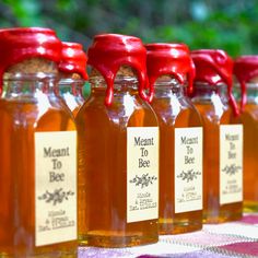 several jars of honey sit on a table with red caps and labels that read meant to bee