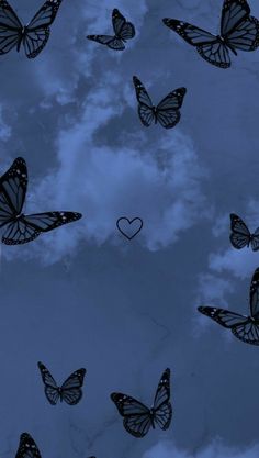 many butterflies flying in the air with a heart shaped object above them on a cloudy day