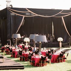 tables set up for an event with red tablecloths and black draping