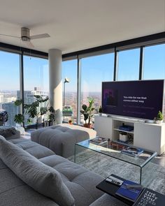 a living room filled with furniture and large windows looking out onto the cityscape