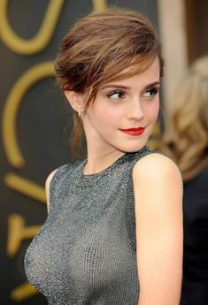 a woman with red lipstick and grey dress posing for the camera at an oscars event