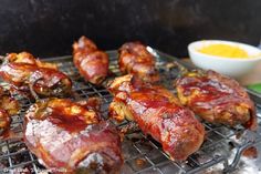 several pieces of meat on a grill with dipping sauce