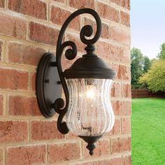 an outdoor wall light on the side of a brick building with grass in the background