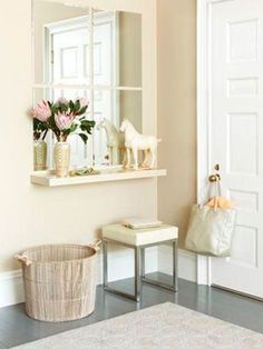 a white room with a mirror, vases and flowers on the window sill