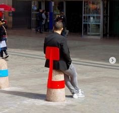 a man sitting on top of two red and blue stools