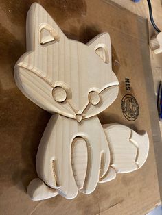 a wooden cutout of a cat sitting on top of a piece of paper next to scissors