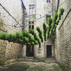 an alley way with moss growing on the stone walls and brick buildings in the background