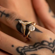 a close up of a person's hand with tattoos on their fingers and an engagement ring