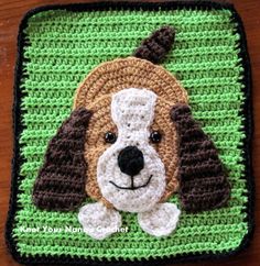 a beaded dog with a hat on it's head sits in front of a green background