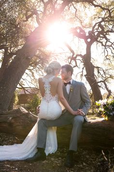 a bride and groom are sitting on a log