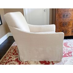 a white chair sitting on top of a rug in a living room next to a dresser