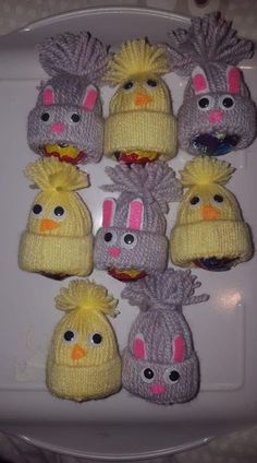 several knitted hats with different faces and hair are arranged on a white platter