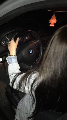 a woman driving a car with her hand on the steering wheel