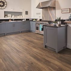 a large kitchen with wood floors and stainless steel appliances on the counter top, along with a clock