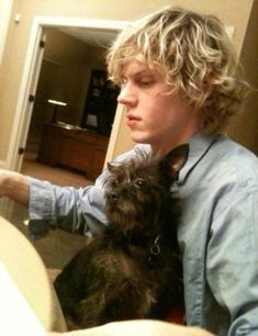 a young man holding a small dog in his lap