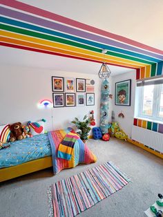 a child's bedroom with rainbow striped walls and rugs on the carpeted floor