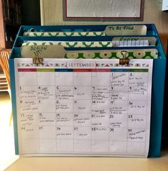 a desk calendar sitting on top of a blue file folder filled with notes and papers