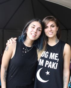 two women standing next to each other in front of a tent