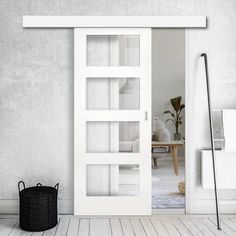 an empty room with a white door and black basket on the floor next to it