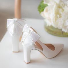 the bride's white shoes are adorned with pearls and bows, along with a bouquet of flowers