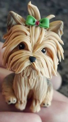 a small dog figurine sitting on top of someone's hand with a green bow