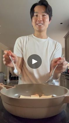 a man standing in front of a frying pan filled with food and eating utensils