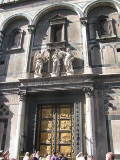 people are standing in front of an ornate building with statues on the doors and windows