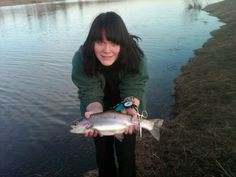 a woman is holding a fish in her hands