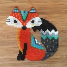 an animal made out of plastic beads sitting on top of a wooden floor next to a wall