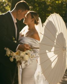 the bride and groom are holding an umbrella