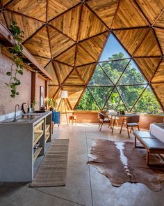 a kitchen and living room inside of a wooden structure with large windows on the side