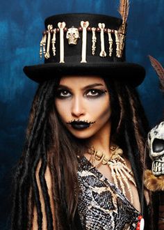 a woman with dreadlocks wearing a top hat and skeleton makeup on her face