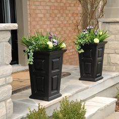 two black planters with flowers on the steps